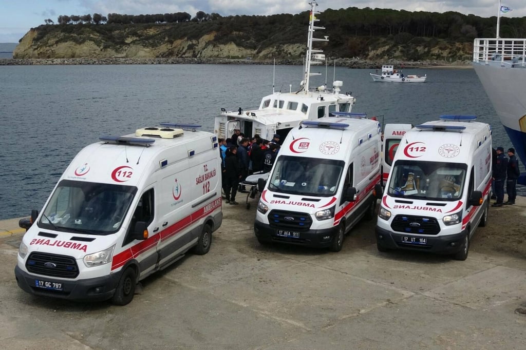 Ambulances parked by a coastguard boat as officials unload bodies of 21 migrants, including five children, that drowned after a boat carrying them capsized off the Turkish coast in the Aegean Sea. Photo: DHA/AFP