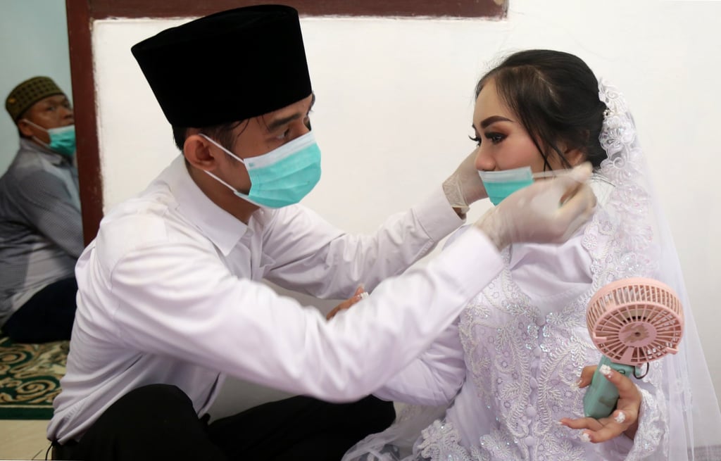 A groom puts a face mask on his bride before their wedding ceremony in Jakarta. Indonesia recorded only 1.79 million marriages in 2020. Photo: AFP A groom puts a face mask on his bride before their wedding ceremony in Jakarta. Indonesia recorded only 1.79 million marriages in 2020. Photo: AFP