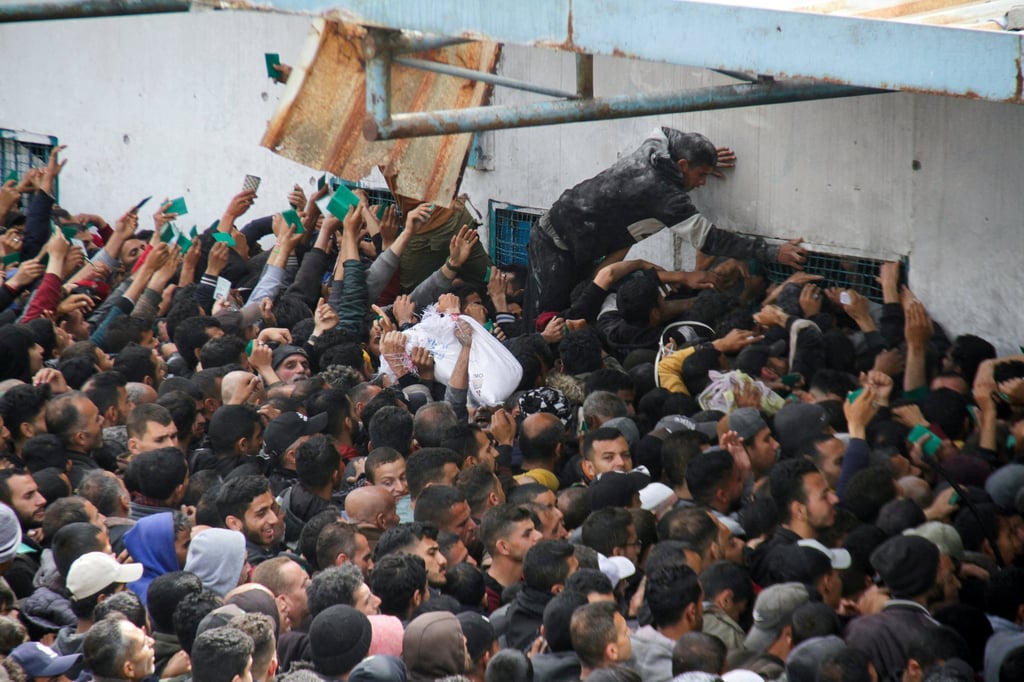 Palestinians gather to receive aid outside an UNRWA warehouse as Gaza residents face crisis levels of hunger. Photo: Reuters