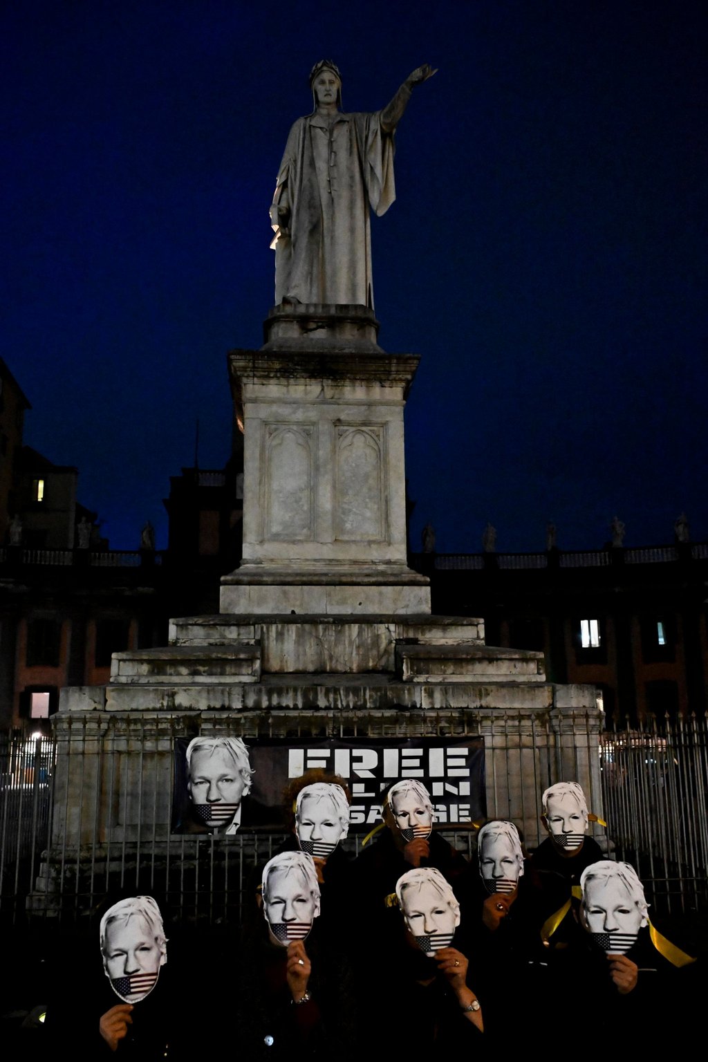 Supporters of WikiLeaks founder Julian Assange wear face masks in front of the Monument to Dante in Naples, Italy on Tuesday. Photo: EPA-EFE