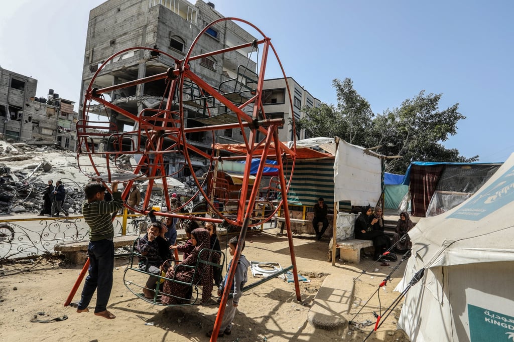 Displaced Palestinian children play between their tents on a swing in the Shaboura refugee camp in Rafah, as Israeli air strikes continue. Photo: dpa