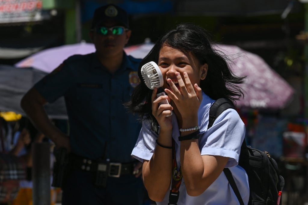 A student uses a portable fan outside a school in Manila on Tuesday. Photo: AFP