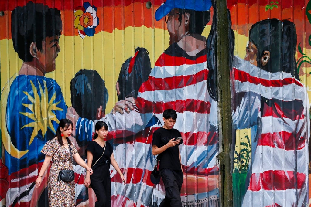 Tourists walk past a mural featuring the Malaysian flag in Kuala Lumpur. Photo: EPA-EFE