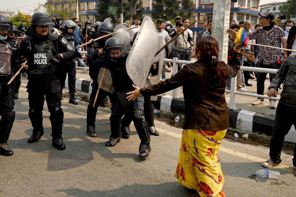Security personnel baton charge a woman during a protest to demand the restoration of monarchy and the status of a Hindu state. Photo: AFP