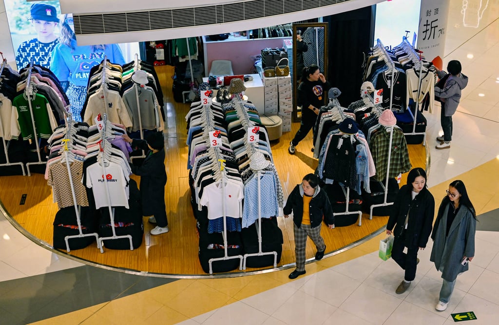 People walk past a clothing store in a shopping centre in Beijing on March 20, 2024. Photo: AFP