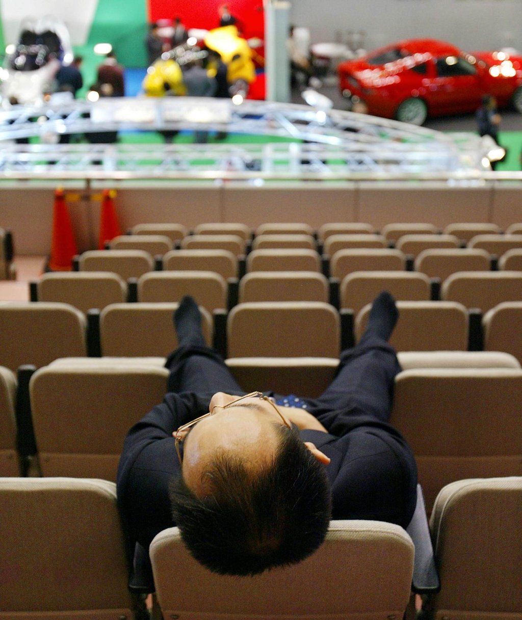 A Japanese businessman has a nap on backs of chairs during a preview of the Tokyo Motor Show in Makuhari, suburban Tokyo. Photo: AFP
