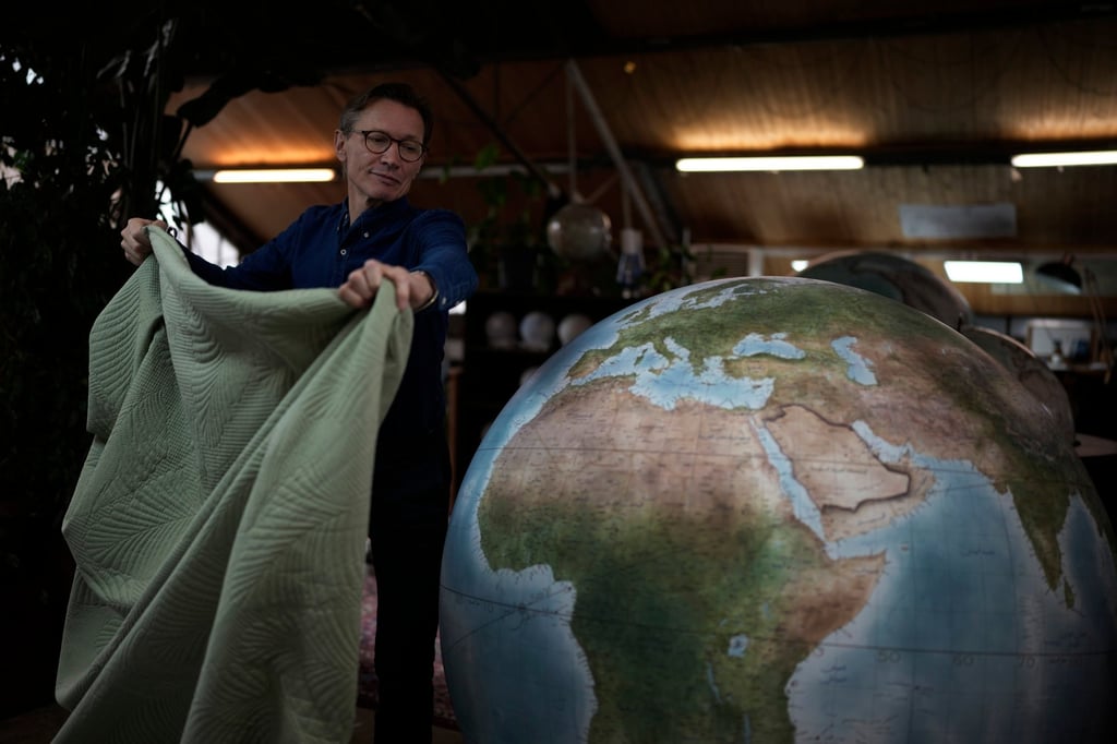 Peter Bellerby, founder of Bellerby & Co Globemakers, covers a globe at his studio in London on February 27, 2024. Photo: AP