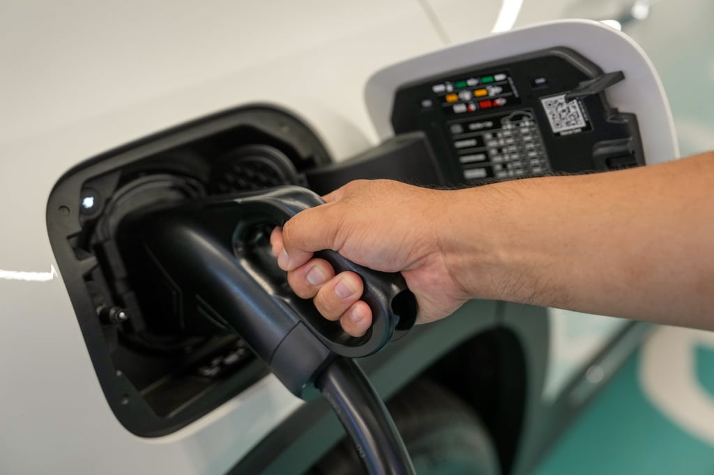 A driver plugs in his electric vehicle at a charging station. Photo: Elson Li