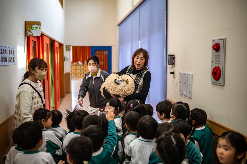 Atsuko Sato and her Japanese shiba inu dog Kabosu, whose picture spawned online memes that led to the cryptocurrency Dogecoin being created, greet children at a kindergarten in Narita, east of Tokyo. Photo: AFP