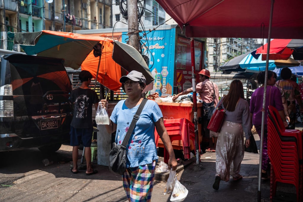A woman walks with a cold drink under an umbrella along a street on a hot day in Yangon. Myanmar recorded its hottest ever April temperature of 48.2 degrees Celsius. Photo: AFP