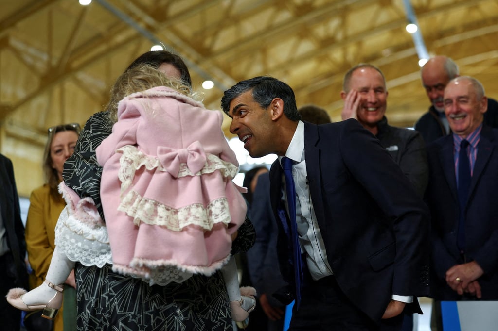Britain’s Prime Minister Rishi Sunak reacts next to a woman carrying a child as he visits Teesside in Tees Valley, Darlington, on Friday. Photo: Reuters