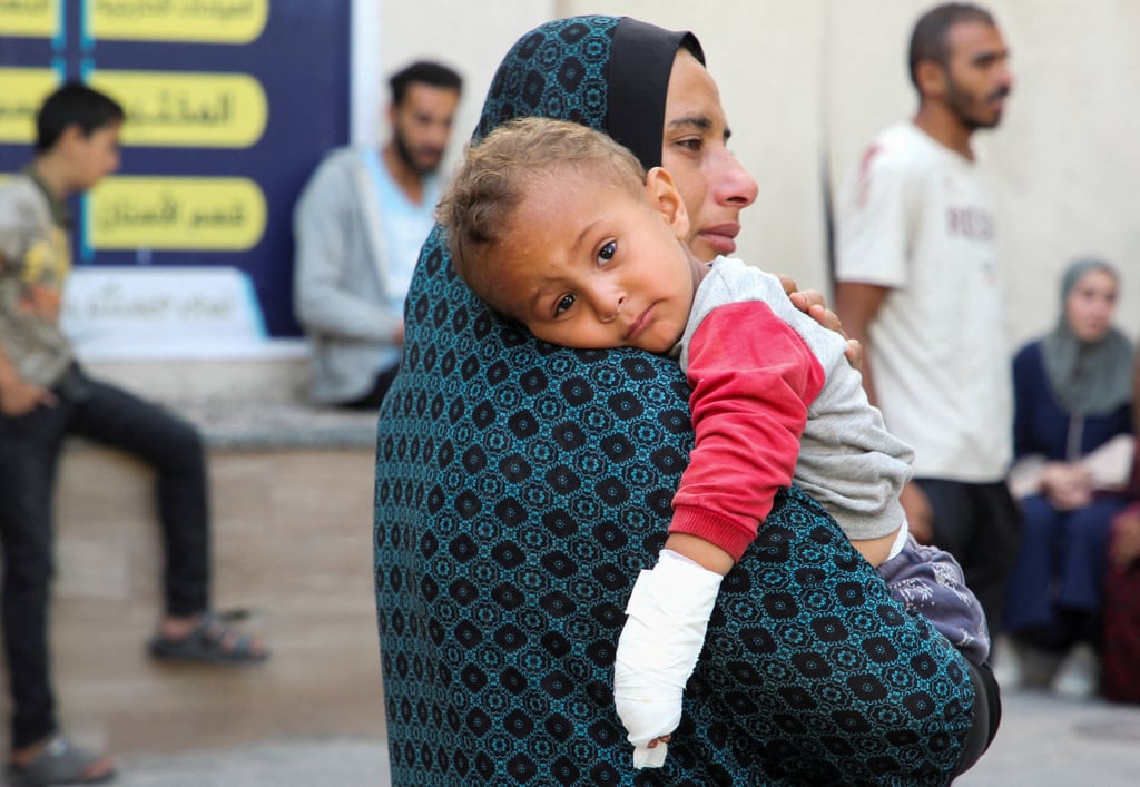 An injured Palestinian child looks on as mourners stand next to the bodies of Palestinians (not pictured) killed in an Israeli strike in Rafah on Friday. Photo: Reuters