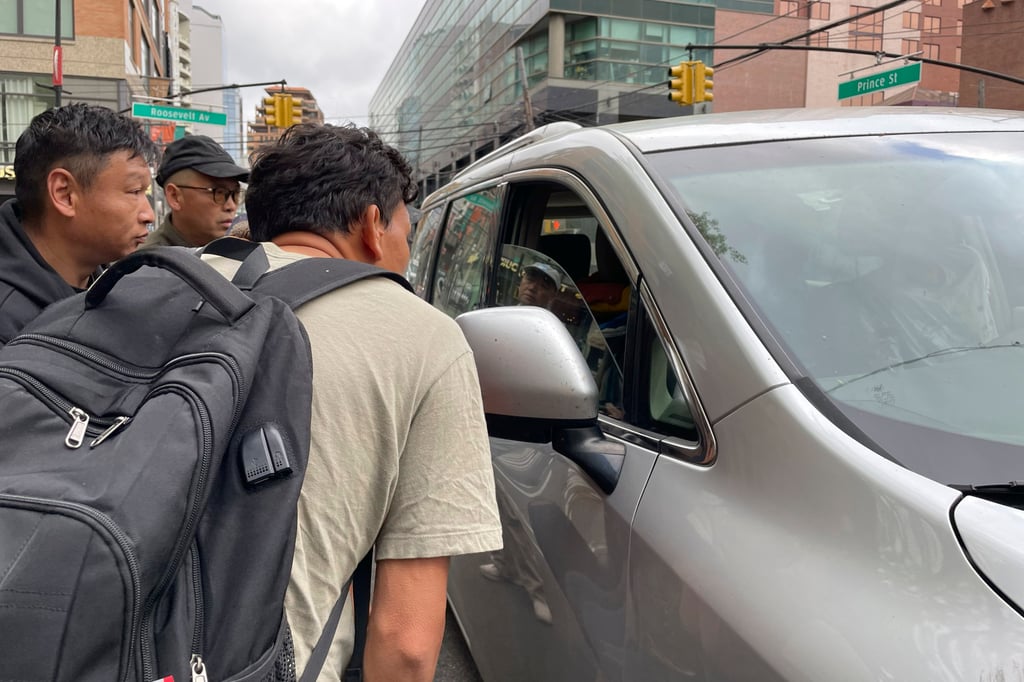 Wang Gang front, a Chinese immigrant, talks with the driver of a car with others as they try to get a daily paid job working construction or in another trade in the Flushing neighbourhood of the Queens borough of New York. Photo: AP Wang Gang front, a Chinese immigrant, talks with the driver of a car with others as they try to get a daily paid job working construction or in another trade in the Flushing neighbourhood of the Queens borough of New York. Photo: AP
