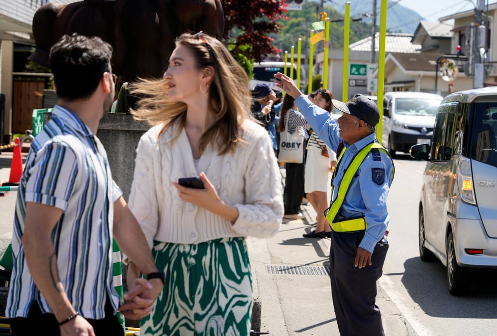 A security guard gestures towards foreign tourists as they gather on a street in Fujikawaguchiko, north of Mount Fuji, earlier this month. Japan has been encouraging immigration in recent years to combat labour shortages. Photo: EPA-EFE
