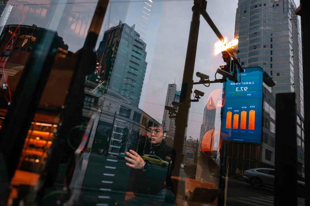 A man works in a shop while a large screen showing the latest stock exchange and economic data is seen reflected on the shop’s window in Shanghai, China, 29 January 2024. Photo: EPA-EFE A man works in a shop while a large screen showing the latest stock exchange and economic data is seen reflected on the shop’s window in Shanghai, China, 29 January 2024. Photo: EPA-EFE