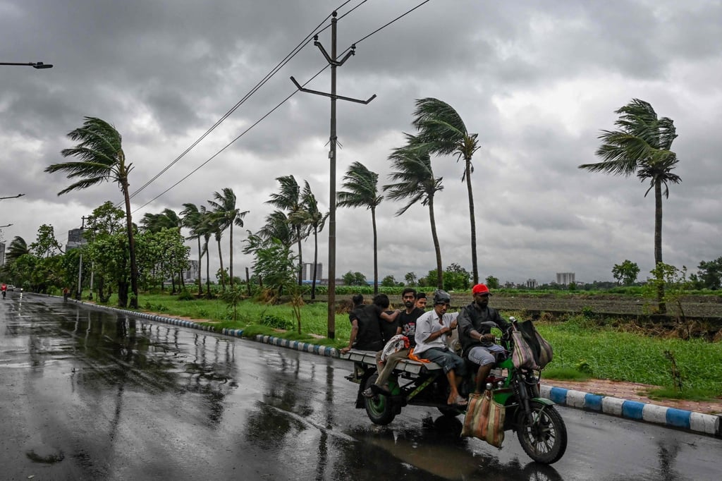Commuters travel on a motorised three-wheeler along a road as rain clouds loom in Kolkata, capital of India’s West Bengal state, on Sunday. Photo: AFP