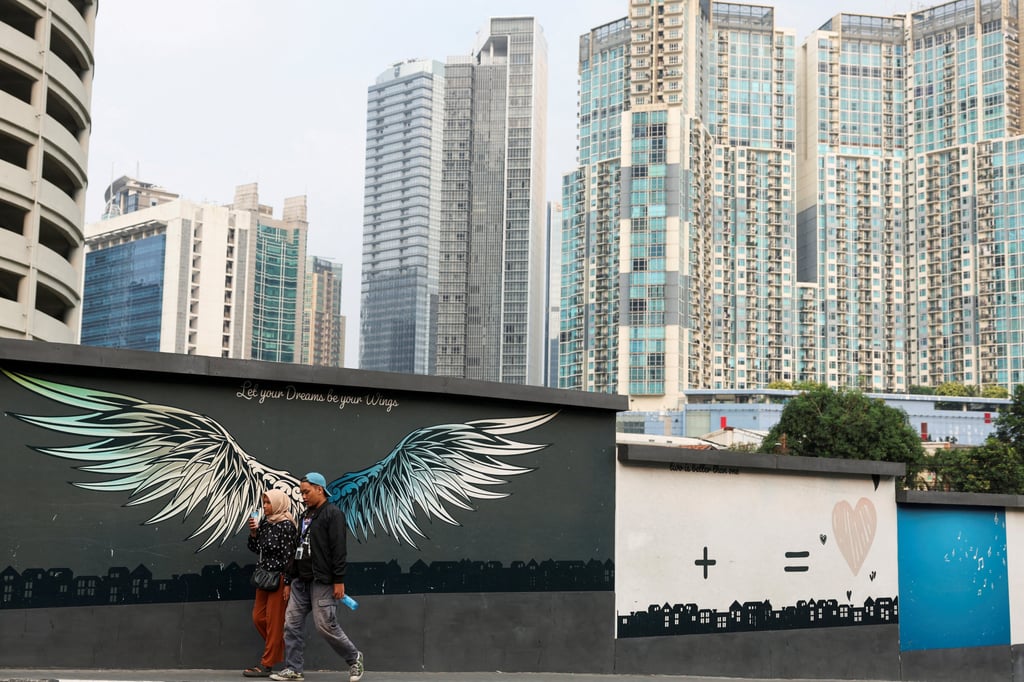 People walk beside a mural depicting wings with a background of office buildings and flats in Jakarta, Indonesia, on May 20. Photo: Reuters