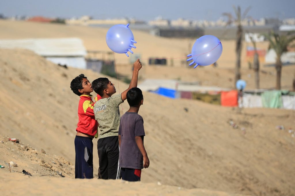 Displaced Palestinian children play with surgical rubber gloves in Rafah on Friday. Photo: AFP
