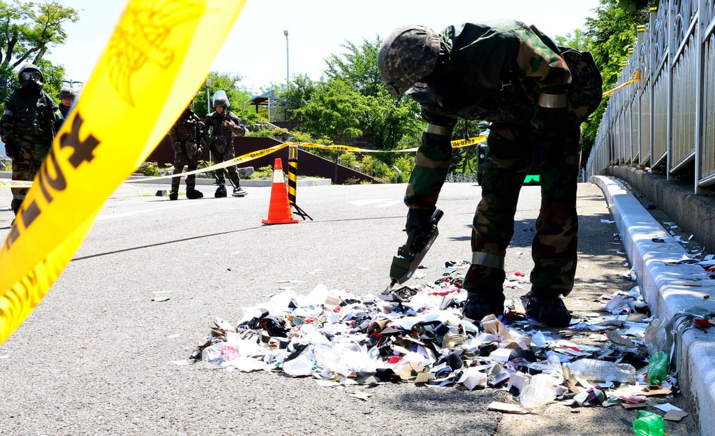 A South Korean soldier wearing protective gear checks the rubbish from a balloon in Incheon on Sunday. Photo: Yonhap via AP