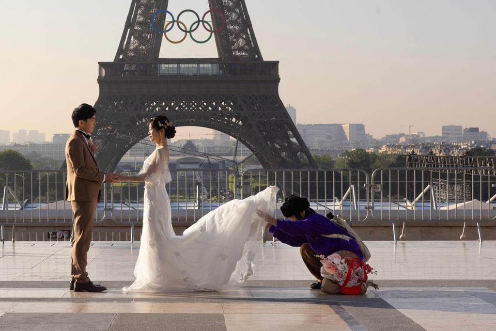 Newlyweds preparing to pose in front of the Eiffel Tower, after the installation of the Olympic rings. Photo: AFP