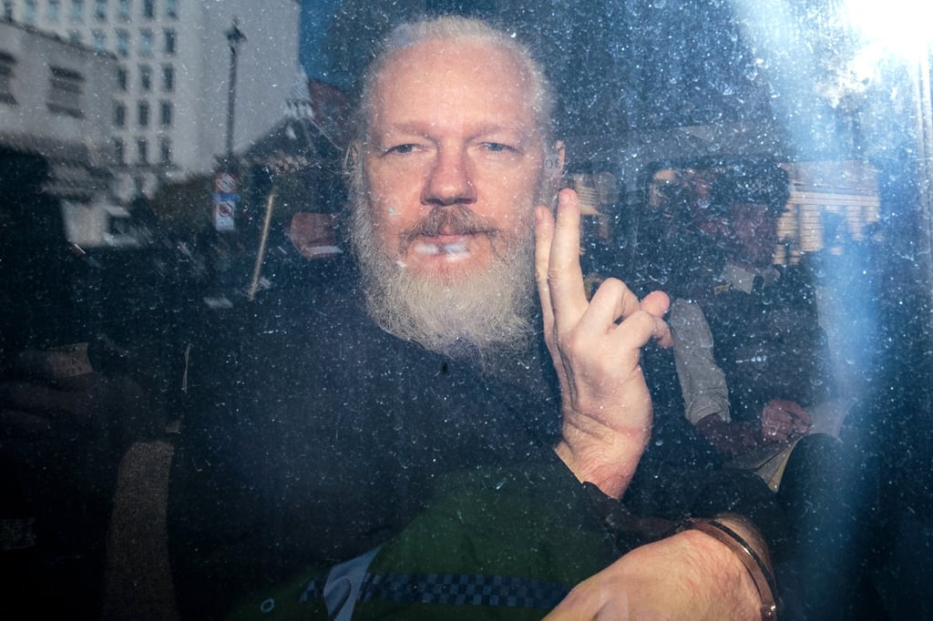 Julian Assange gestures to the media from a police vehicle on his arrival at Westminster Magistrates court on April 11, 2019, in London. Photo: TNS