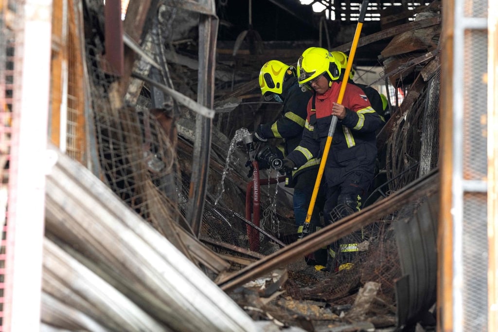Firefighters walk through the wreckage and debris after a fire at a pet market next to Chatuchak market in Bangkok on Tuesday. Photo: AFP