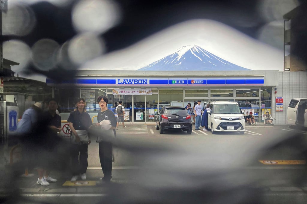 Mt Fuji is seen through a hole poked in a black screen installed to stop tourists taking photos of the mountain with a convenience store in Fujikawaguchiko in the foreground. Photo: Kyodo News/AP