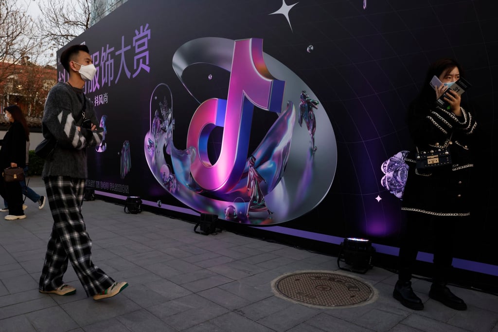 A woman speaks on her phone near the logo for Douyin in Beijing, March 31, 2021. Photo: AP