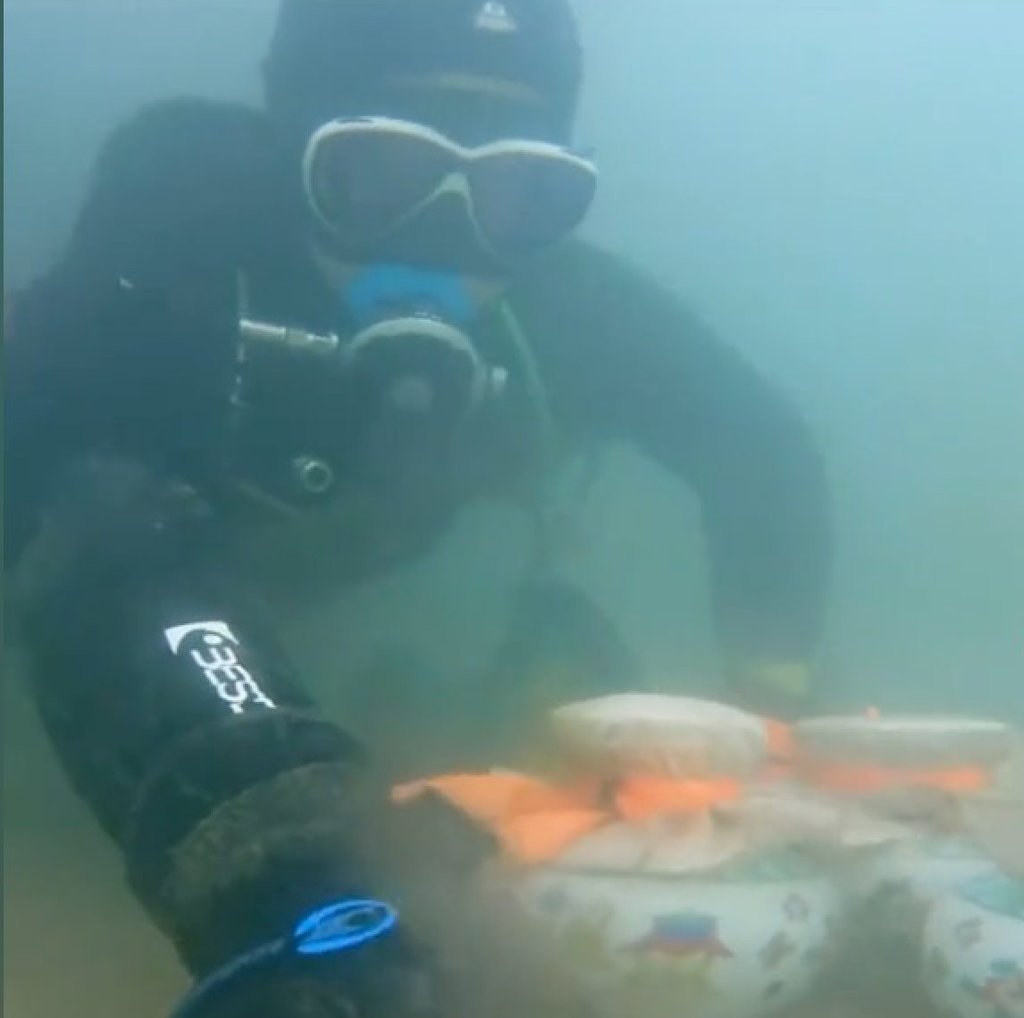 The veteran diver with the sealed urns which he thought could be from a sea burial. Photo: Douyin