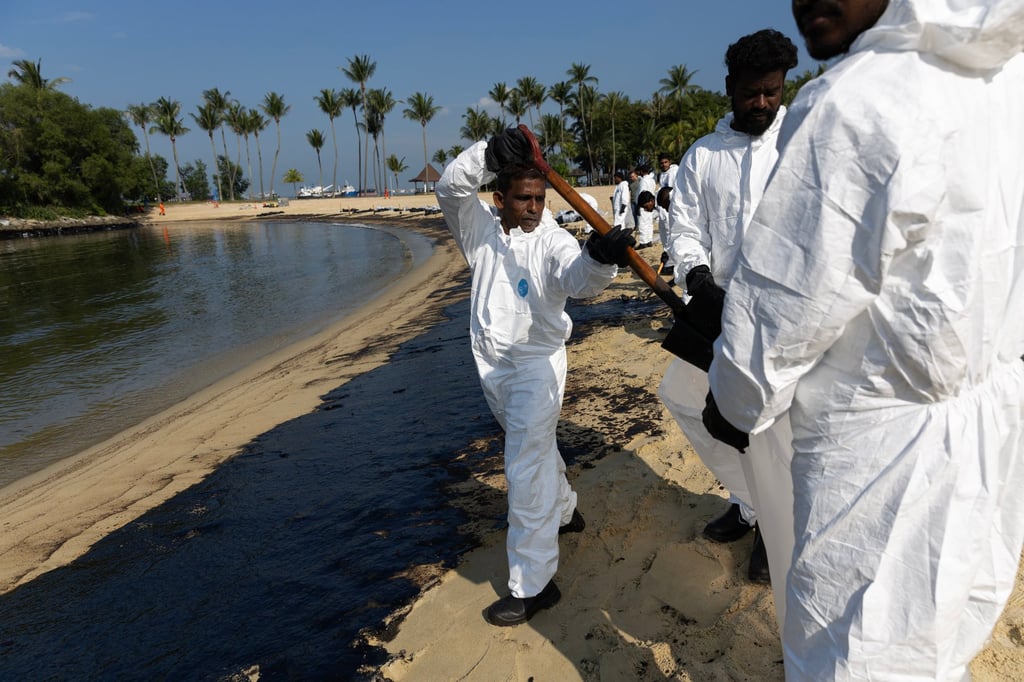 Workers clean up an oil slick from the ship collision at Sentosa Island’s Tanjong Beach on Monday. Photo: EPA-EFE