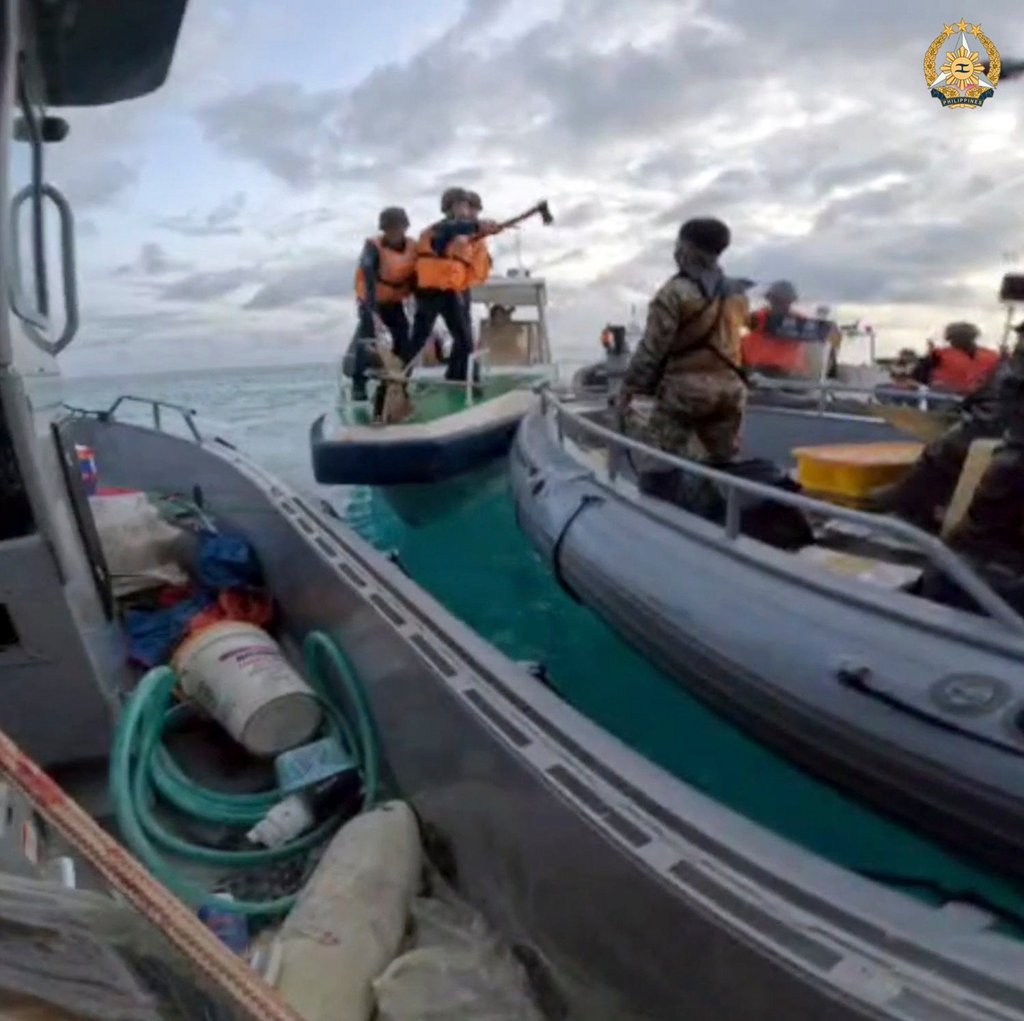Chinese coastguard personnel hold an axe as they approach Philippine troops on a resupply mission in the Second Thomas Shoal at the disputed South China Sea on Monday. Photo: AP
