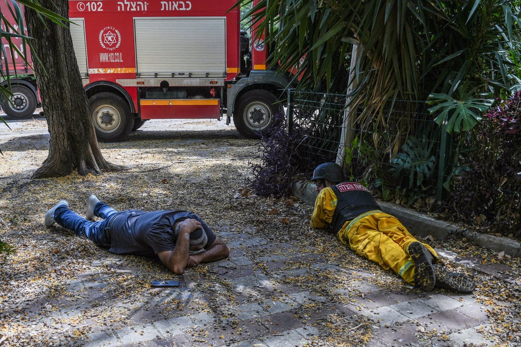 Men take cover from incoming rockets in Kiryat Shmona, northern Israel Photo: Reuters