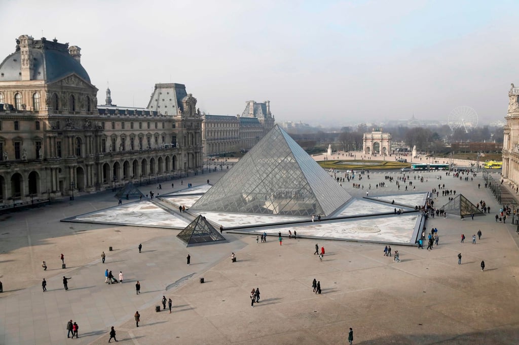 People walk around the pyramid of the Louvre, designed by architect I.M. Pei, in 2017. Photo: AFP