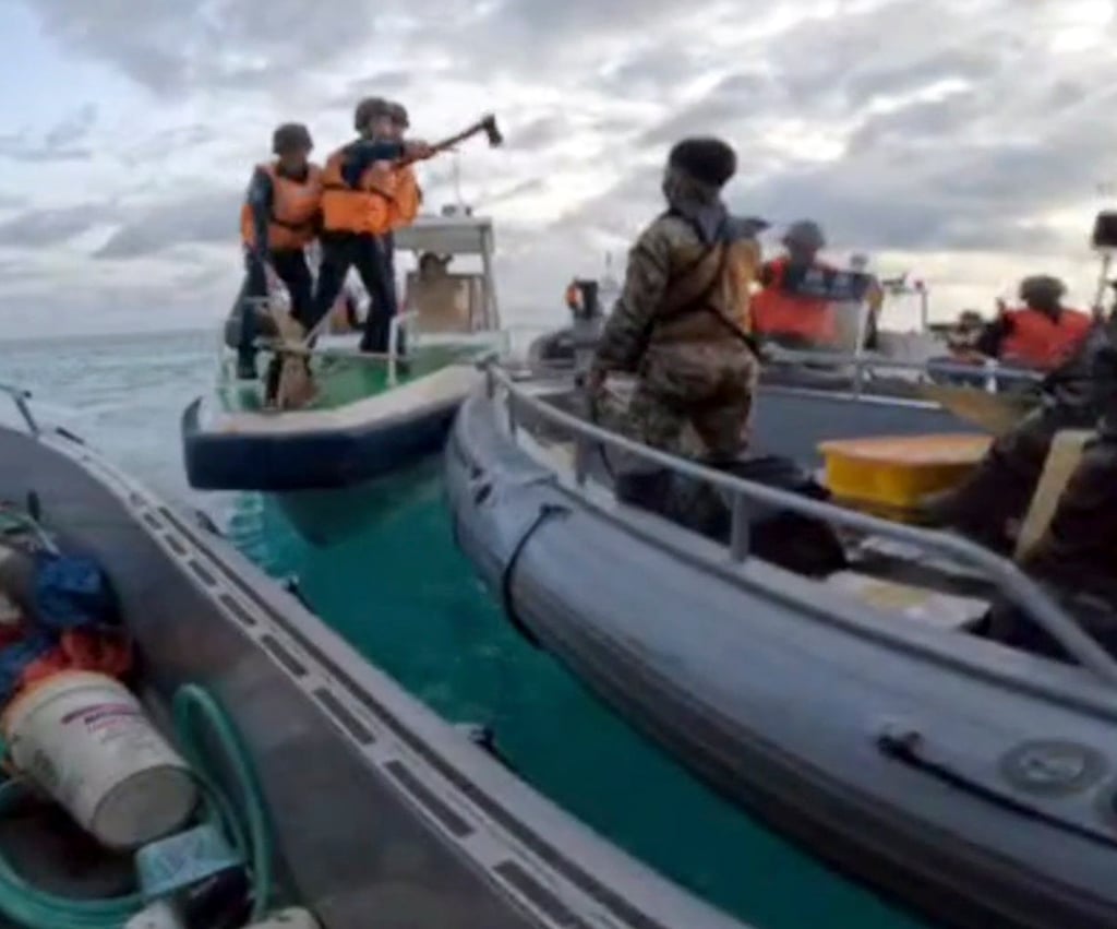 Chinese coastguard personnel hold an axe as they approach Filipino troops on a resupply mission to Second Thomas Shoal in the South China Sea on June 17. Photo: Armed Forces of the Philippines/Handout via AP