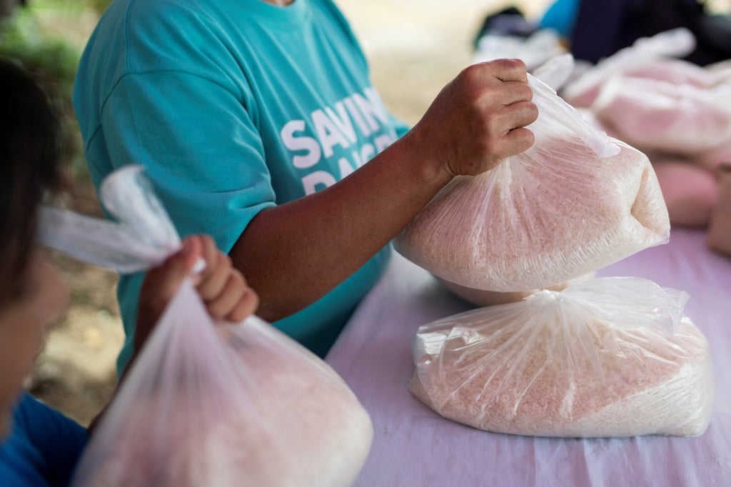 A woman receives a plastic bag of rice in exchange for picking up plastic waste in the Philippines. Photo: Reuters A woman receives a plastic bag of rice in exchange for picking up plastic waste in the Philippines. Photo: Reuters
