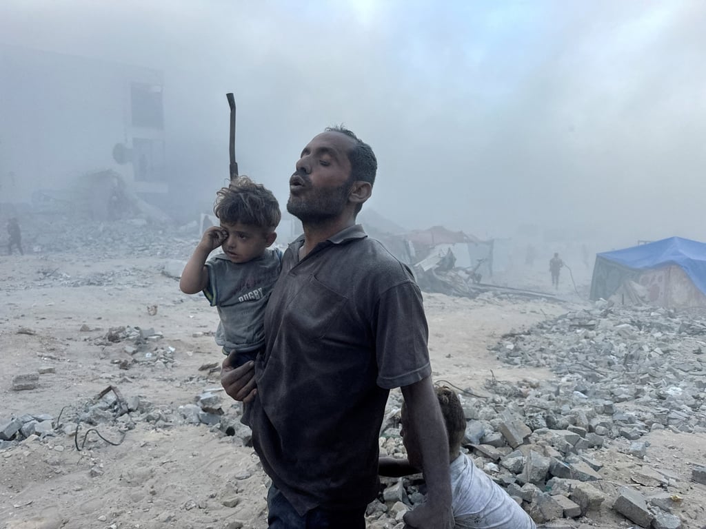 A Palestinian man carries a child after an Israeli strike near a UN-run school sheltering displaced people in Khan Younis on Wednesday. Photo: Reuters