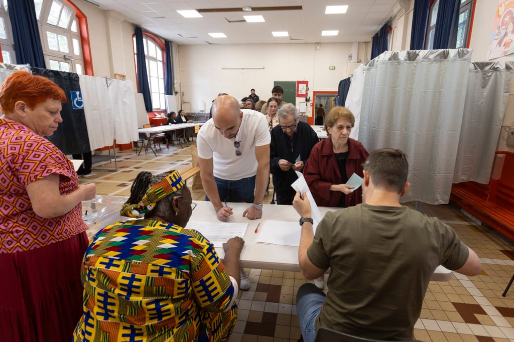 French citizens queue as they wait to cast their ballot during the second round of French parliamentary elections at a polling station in the 18th District in Paris on Sunday. Photo: EPA-EFE