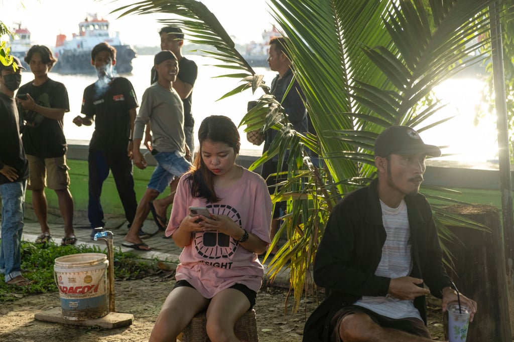 Young people hang out on the Segai River waterfront. Photo: Oliver Raw