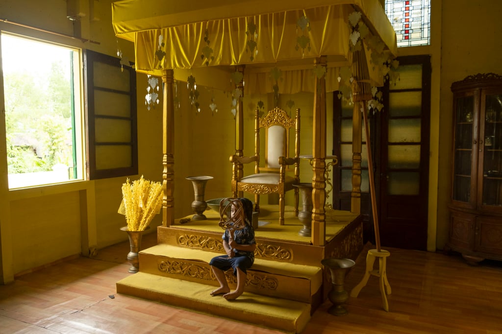 A child sits on steps in the sultan’s throne room at Sambuliang Palace. Photo: Oliver Raw