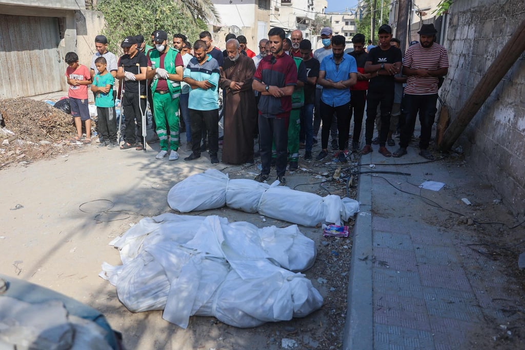 People pray by bodies in Gaza City on Friday. Photo: AFP People pray by bodies in Gaza City on Friday. Photo: AFP