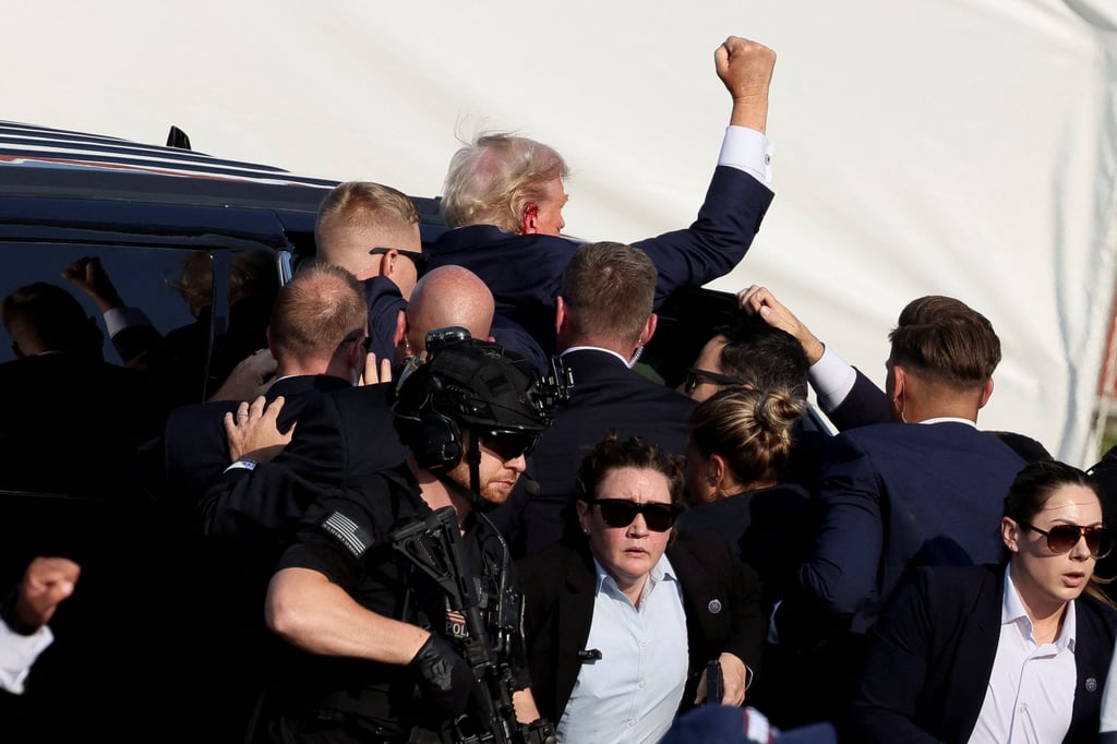 Trump gestures as he gets into a vehicle with the assistance of Secret Service personnel after he was shot. Photo: Reuters