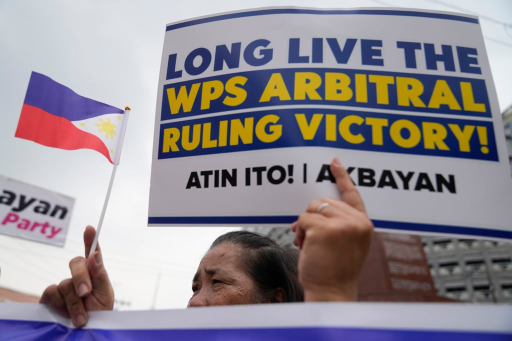 A demonstrator holds a slogan and a small Philippine flag to celebrate the eighth anniversary of an arbitration ruling that invalidated Beijing’s vast territorial claims in the South China Sea, as they hold a rally in Quezon City on Friday. Photo: AP