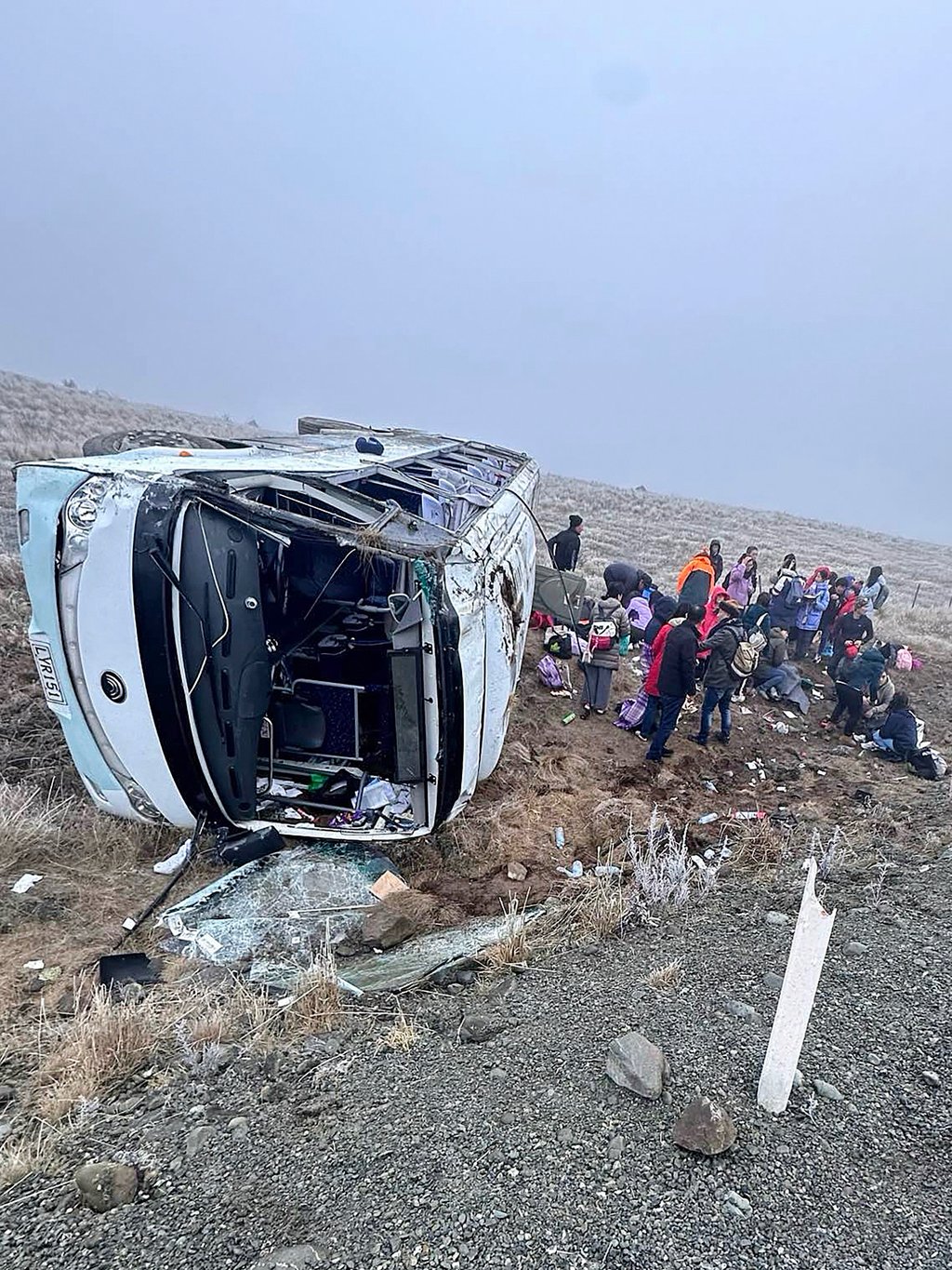 Passengers are seen beside one of the crashed Chinese tour buses near Lake Tekapo on Thursday. Photo: Grace Duggin/via AP