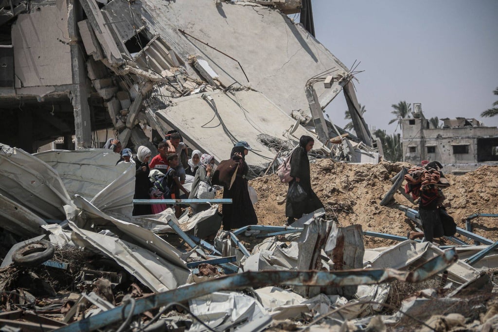 Displaced Palestinians pass destroyed buildings as they leave Khan Younis, southern Gaza on Monday. Photo: Bloomberg Displaced Palestinians pass destroyed buildings as they leave Khan Younis, southern Gaza on Monday. Photo: Bloomberg