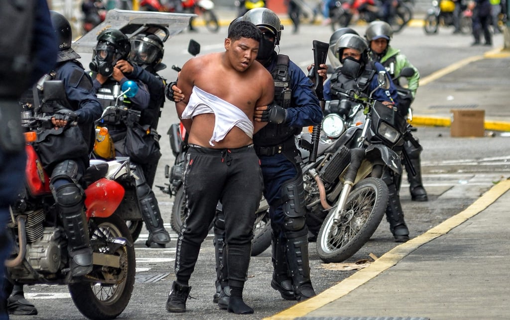 Members of the Bolivarian National police riot squad arrest an opponent of Maduro taking part in a protest in Caracas on Wednesday. Photo: AFP Maduro pide al Tribunal Supremo de Justicia que audite las elecciones en disputa