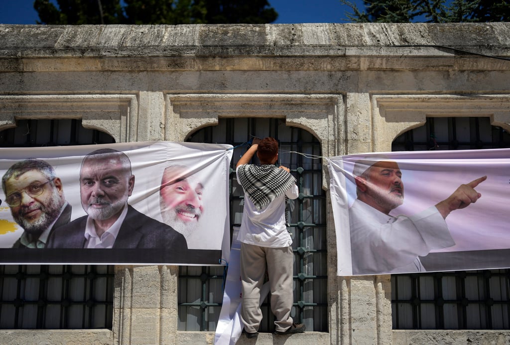 A man hangs banners with pictures of Haniyeh, outside the Fatih mosque in Istanbul, Turkey. Photo: AP