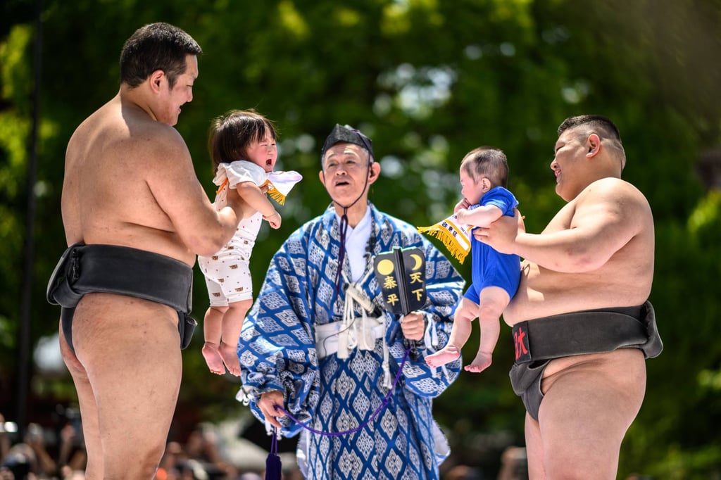 Sumo wrestlers hold children during their “crying baby sumo” match at Sensoji temple in Tokyo. Japan has introduced up to one-year paternity leave but the take-up rate is low. Photo: AFP
