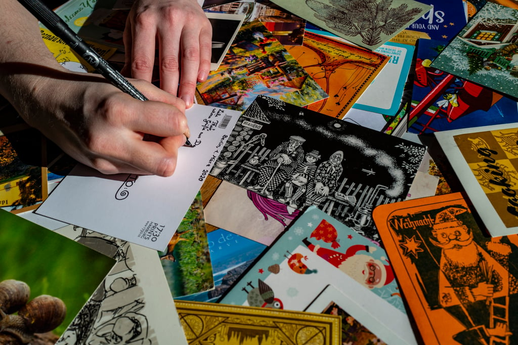 Postcard enthusiast Gesa Funke writes on a postcard in her flat in Berlin, Germany, in 2021, during the coronavirus pandemic. Photo: AFP