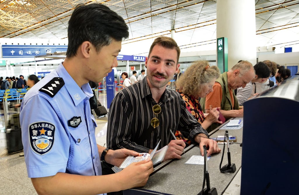 A police officer assists an American tourist fill out an entry registration card at the border check section of Beijing Capital International Airport in China. Photo: Xinhua