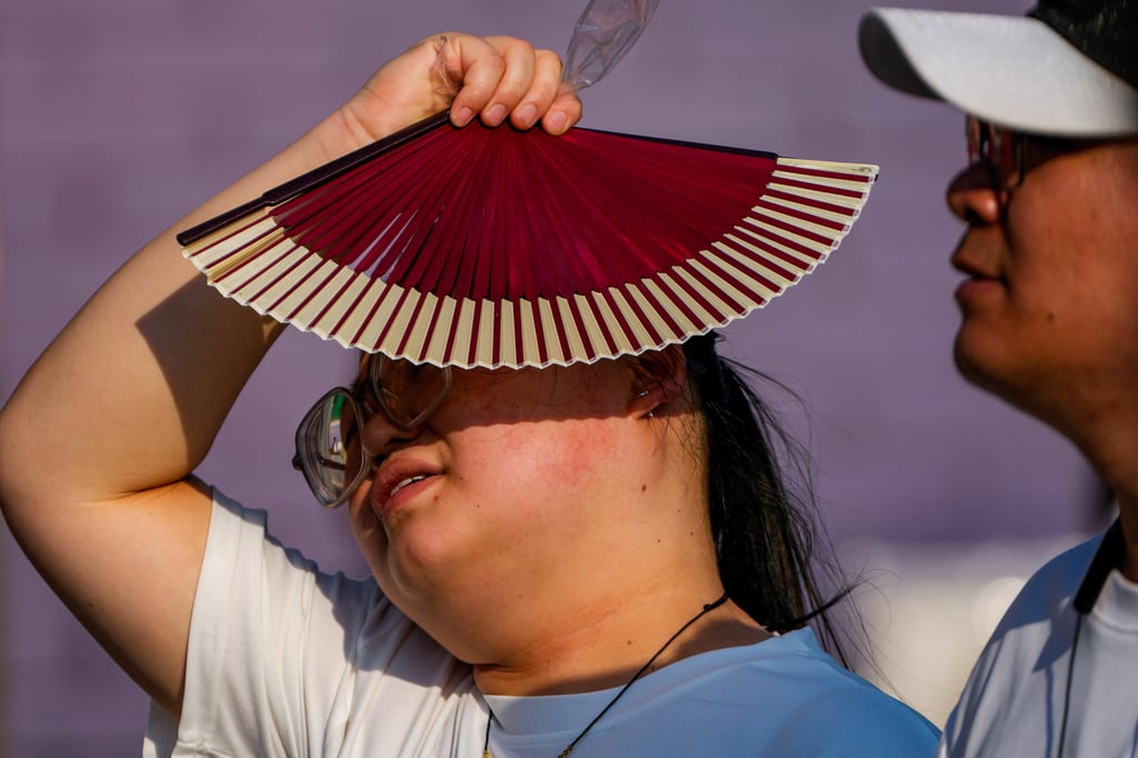 A woman uses a fan to block the sun on an unseasonably hot day in Beijing, June 16, 2024. Photo: AP A woman uses a fan to block the sun on an unseasonably hot day in Beijing, June 16, 2024. Photo: AP